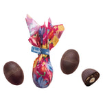 Venchi Bitterschokoladeneier mit gerösteter, ganzer Haselnuss 100 g: Ein Schokoladenei in floralem Papier, eine Haselnuss und ein Stück Bitterschokolade dekorativ arrangiert.
